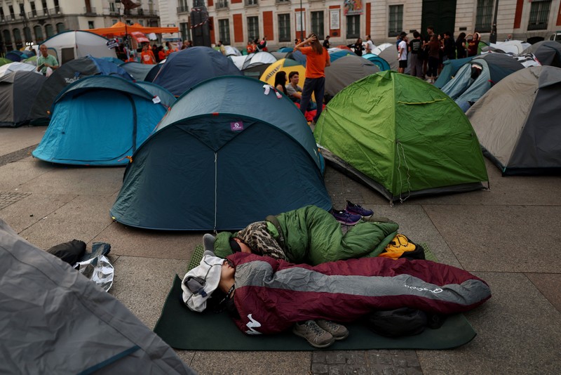 Para demonstran tidur dan berkumpul di sekitar tenda setelah mendirikan perkemahan di alun-alun Puerta del Sol sebagai protes terhadap krisis perumahan di Spanyol menyusul penggusuran paksa seorang wanita berusia 87 tahun dari apartemennya di Madrid, Spanyol, 27 September 2026. REUTERS/Susana Vera
