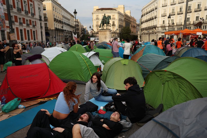 Para demonstran tidur dan berkumpul di sekitar tenda setelah mendirikan perkemahan di alun-alun Puerta del Sol sebagai protes terhadap krisis perumahan di Spanyol menyusul penggusuran paksa seorang wanita berusia 87 tahun dari apartemennya di Madrid, Spanyol, 27 September 2026. REUTERS/Susana Vera
