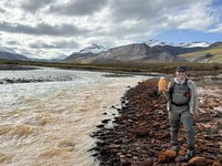 Taylor Evinger, seorang kandidat doktor di UC Davis, memegang botol berisi air berwarna oranye yang diambil dari Sungai Igning di Gates of the Arctic National Park and Preserve, Alaska. (Dokumentasi: Taylor Evinger/UC Davis)