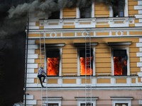 A man uses a ladder as flames rise from an administrative building hit by a Russian jet-powered drone strike, amid Russia's attack on Ukraine, in Kyiv, Ukraine, September 28, 2026. REUTERS/Thomas Peter