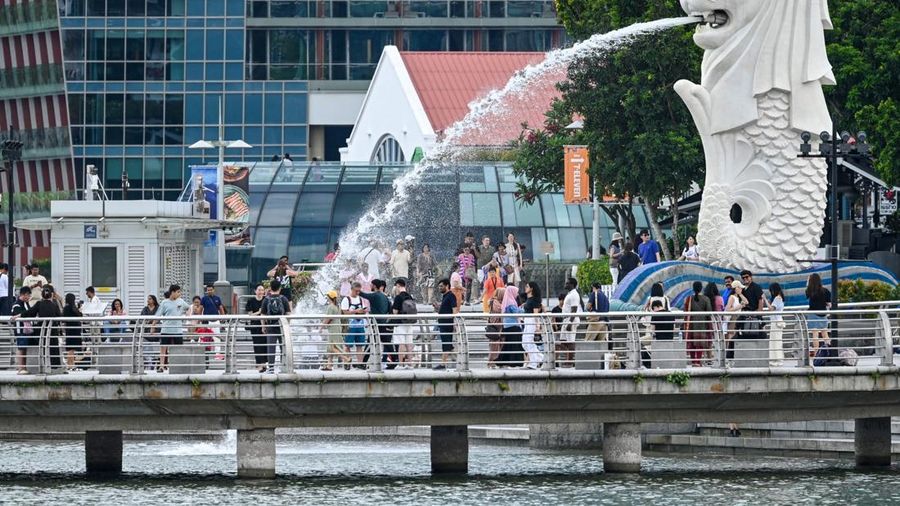 People gather around the Merlion statue at the Marina Bay waterfront in Singapore on May 13, 2024. (Photo by Roslan RAHMAN / AFP)