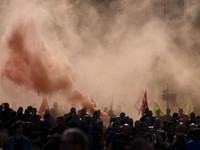 Para pengunjuk rasa berpawai melintasi kepulan asap merah dalam demonstrasi yang dilakukan oleh petugas pemadam kebakaran dan pekerja sektor publik Prancis untuk menuntut kondisi kerja yang lebih baik serta sumber daya tambahan, di Paris, sebagai bag