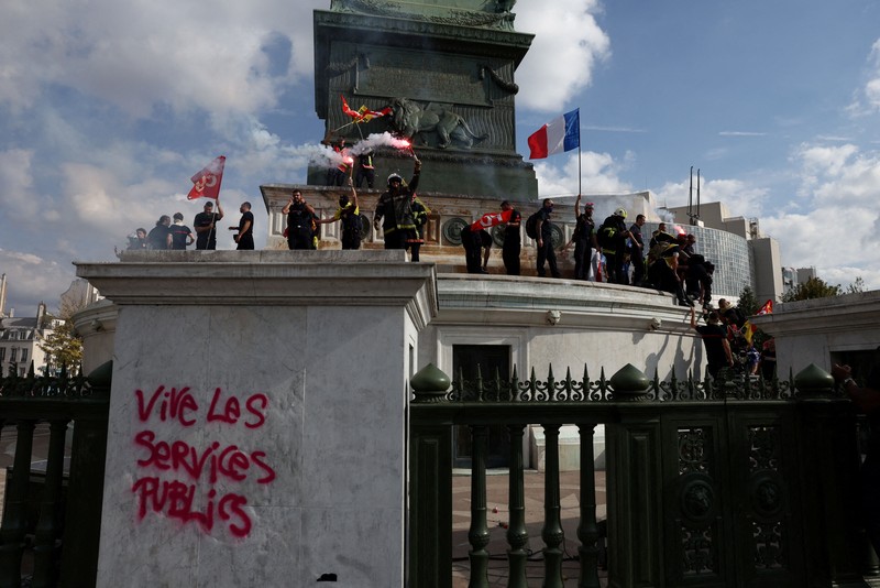 Petugas pemadam kebakaran Prancis membentangkan bendera Prancis saat unjuk rasa yang menuntut tambahan sumber daya dan pendanaan&mdash;menyusul musim panas yang diwarnai kebakaran hebat&mdash;di Paris sebagai bagian dari aksi mogok kerja dan protes oleh pekerja sektor publik di Prancis pada 29 September 2026. (REUTERS/Tom Nicholson)