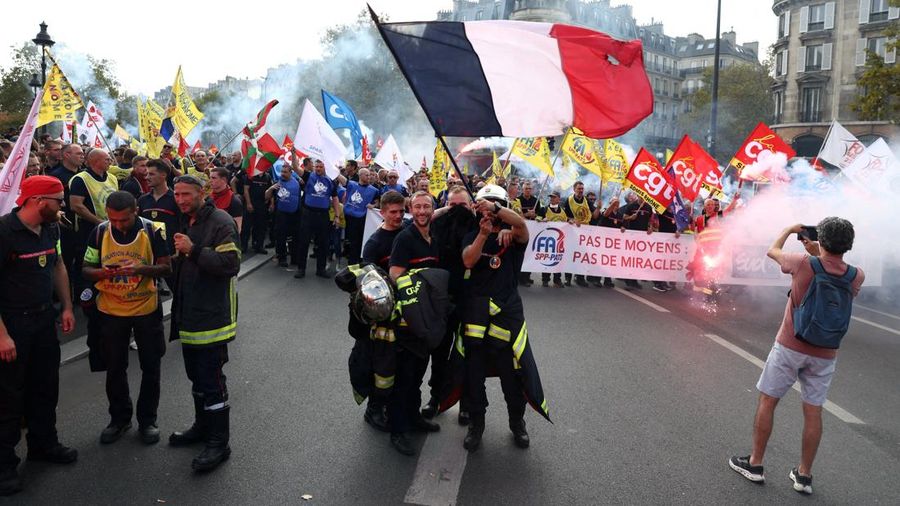 Petugas pemadam kebakaran Prancis membentangkan bendera Prancis saat unjuk rasa yang menuntut tambahan sumber daya dan pendanaanmenyusul musim panas yang diwarnai kebakaran hebatdi Paris sebagai bagian dari aksi mogok kerja dan protes oleh pekerja se