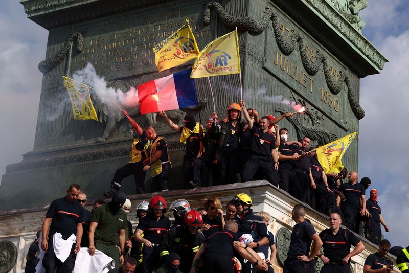 Petugas pemadam kebakaran Prancis membentangkan bendera Prancis saat unjuk rasa yang menuntut tambahan sumber daya dan pendanaan&mdash;menyusul musim panas yang diwarnai kebakaran hebat&mdash;di Paris sebagai bagian dari aksi mogok kerja dan protes oleh pekerja sektor publik di Prancis pada 29 September 2026. (REUTERS/Tom Nicholson)