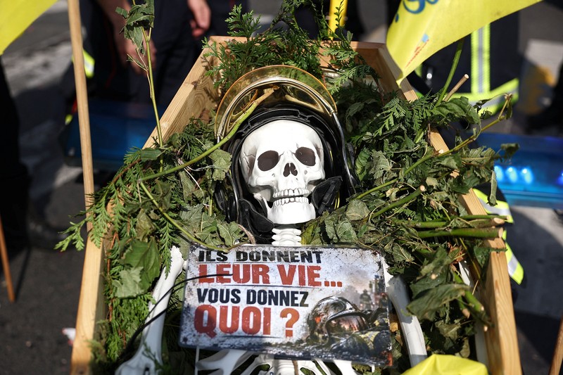 Petugas pemadam kebakaran Prancis membentangkan bendera Prancis saat unjuk rasa yang menuntut tambahan sumber daya dan pendanaan&mdash;menyusul musim panas yang diwarnai kebakaran hebat&mdash;di Paris sebagai bagian dari aksi mogok kerja dan protes oleh pekerja sektor publik di Prancis pada 29 September 2026. (REUTERS/Tom Nicholson)