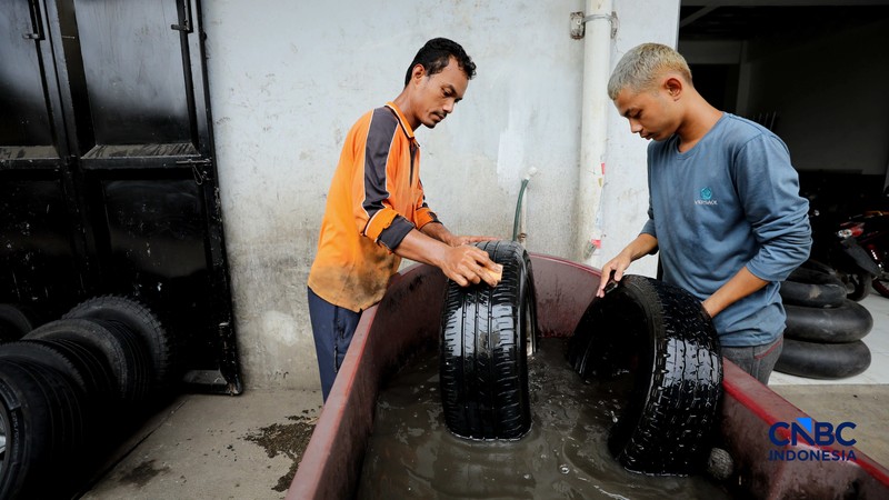 Pekerja mencuci ban bekas di sentra pengempul ban bekas di kawasan Sasak Panjang, Tajur Halang, Bogor, Jawa Barat, Kamis (1/10/2026). Tumpukan ban mobil bekas ini dibeli dari bengkel-bengkel ban wilayah Jabodetabek.  (CNBC Indonesia/Tri Susilo)