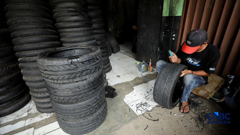Pekerja mencuci ban bekas di sentra pengempul ban bekas di kawasan Sasak Panjang, Tajur Halang, Bogor, Jawa Barat, Kamis (1/10/2026). Tumpukan ban mobil bekas ini dibeli dari bengkel-bengkel ban wilayah Jabodetabek.  (CNBC Indonesia/Tri Susilo)