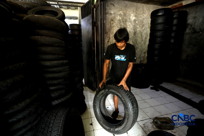 Pekerja mencuci ban bekas di sentra pengempul ban bekas di kawasan Sasak Panjang, Tajur Halang, Bogor, Jawa Barat, Kamis (1/10/2026). Tumpukan ban mobil bekas ini dibeli dari bengkel-bengkel ban wilayah Jabodetabek.  (CNBC Indonesia/Tri Susilo)