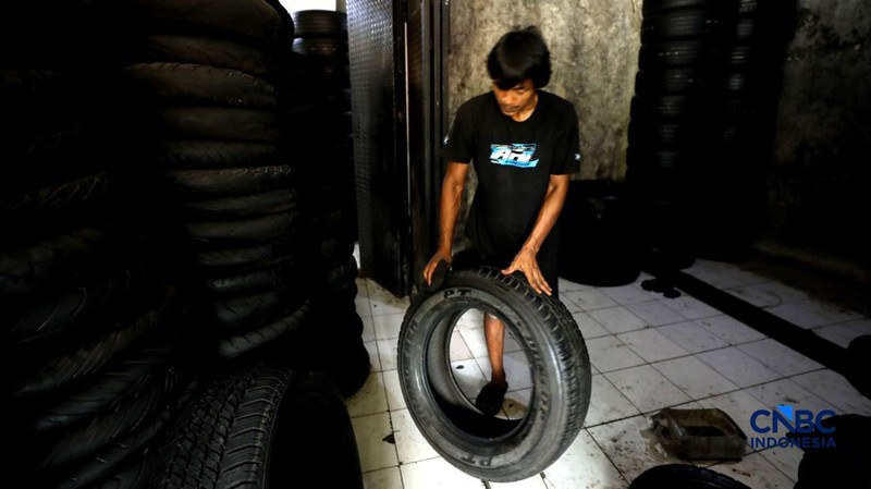 Pekerja mencuci ban bekas di sentra pengempul ban bekas di kawasan Sasak Panjang, Tajur Halang, Bogor, Jawa Barat, Kamis (1/10/2026). Tumpukan ban mobil bekas ini dibeli dari bengkel-bengkel ban wilayah Jabodetabek.  (CNBC Indonesia/Tri Susilo)