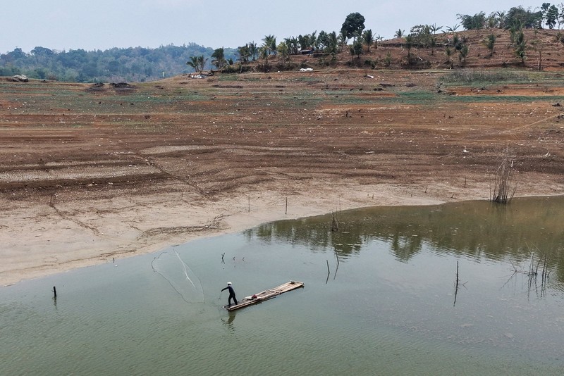 Warga melintas di dekat reruntuhan yang kembali muncul seiring surutnya permukaan air Waduk Jatigede akibat kekeringan di musim kemarau di Kabupaten Sumedang, Jawa Barat, Indonesia, Kamis (1/10/2026). (REUTERS/Claudio Pramana)