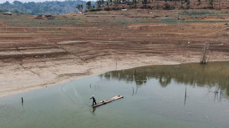 Warga melintas di dekat reruntuhan yang kembali muncul seiring surutnya permukaan air Waduk Jatigede akibat kekeringan di musim kemarau di Kabupaten Sumedang, Jawa Barat, Indonesia, Kamis (1/10/2026). (REUTERS/Claudio Pramana)