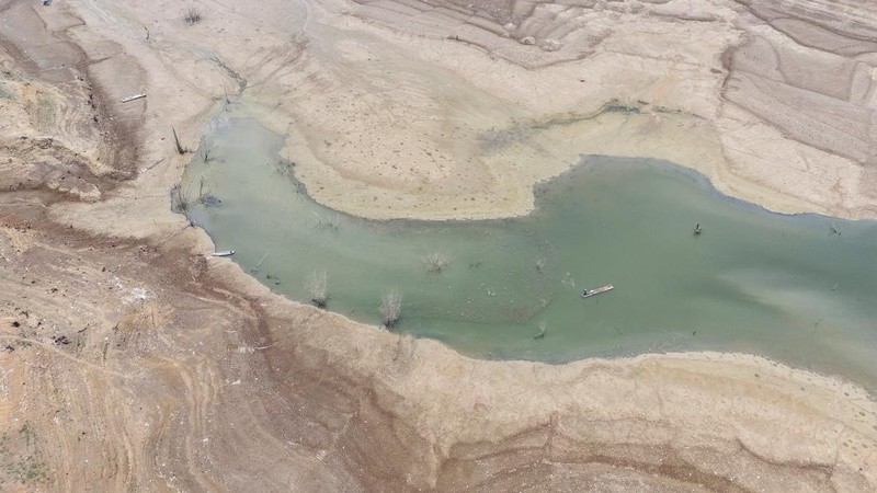 Warga melintas di dekat reruntuhan yang kembali muncul seiring surutnya permukaan air Waduk Jatigede akibat kekeringan di musim kemarau di Kabupaten Sumedang, Jawa Barat, Indonesia, Kamis (1/10/2026). (REUTERS/Claudio Pramana)