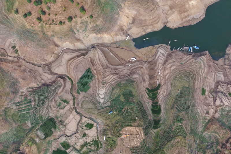 Warga melintas di dekat reruntuhan yang kembali muncul seiring surutnya permukaan air Waduk Jatigede akibat kekeringan di musim kemarau di Kabupaten Sumedang, Jawa Barat, Indonesia, Kamis (1/10/2026). (REUTERS/Claudio Pramana)
