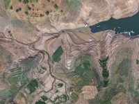 Warga melintas di dekat reruntuhan yang kembali muncul seiring surutnya permukaan air Waduk Jatigede akibat kekeringan di musim kemarau di Kabupaten Sumedang, Jawa Barat, Indonesia, Kamis (1/10/2026). (REUTERS/Claudio Pramana)