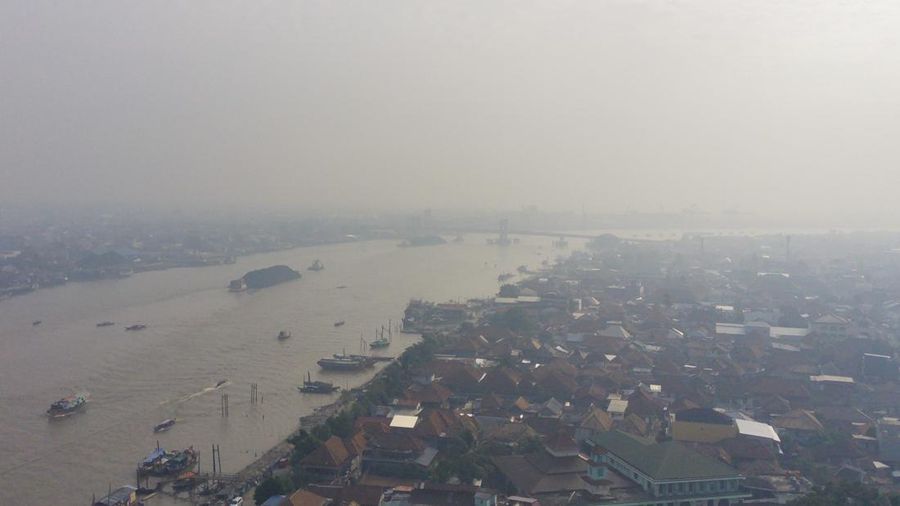 Foto udara memperlihatkan Sungai Musi di tengah kabut asap akibat kebakaran hutan dan lahan yang sedang berlangsung di Palembang, Sumatra Selatan, pada 14 September 2023. (Al ZULKIFLI / AFP)