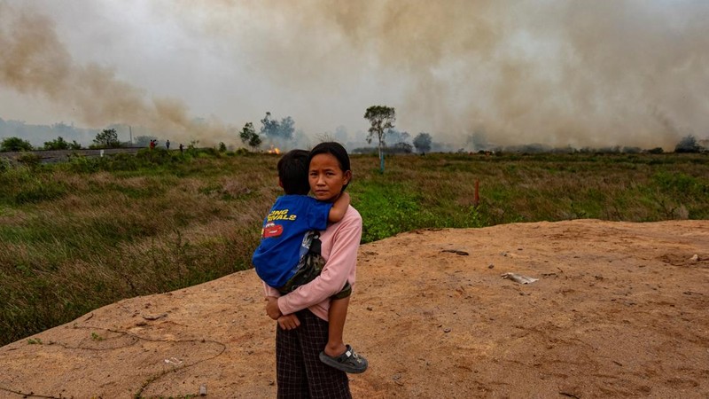 Poppy (12) memeluk adiknya saat petugas pemadam kebakaran Indonesia berupaya memadamkan kebakaran lahan gambut di dekat rumahnya di Palembang, Sumatra Selatan. (Al ZULKIFLI / AFP)