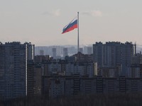 Sebuah bendera nasional Rusia berukuran raksasa berkibar di belakang blok-blok apartemen di Saint Petersburg, Rusia, pada 19 Februari 2025. (REUTERS/Anton Vaganov/File Foto)