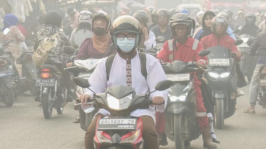 Warga melintasi jalan saat kabut asap akibat kebakaran hutan dan lahan menyelimuti Palembang, Sumatra Selatan, pada 2 Oktober 2026. Kebakaran hutan dan lahan di Indonesia sebagian besar disebabkan oleh praktik pembukaan lahan dengan cara membakar, ya