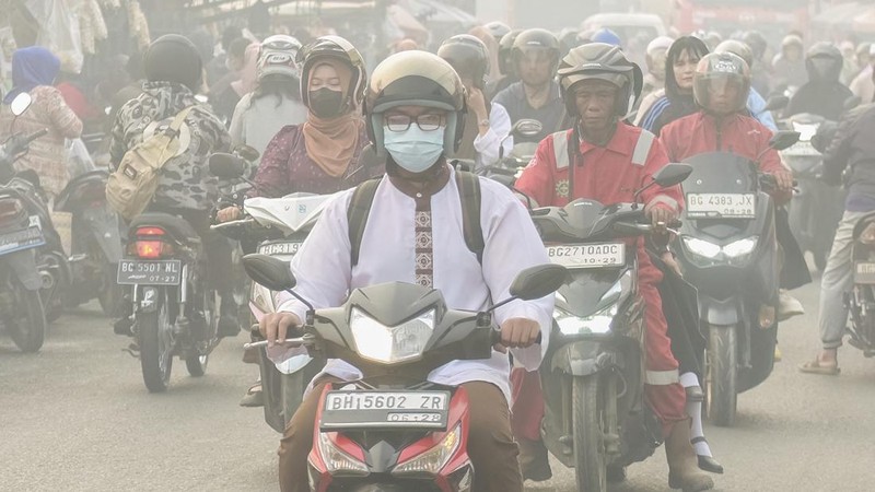 Warga melintasi jalan saat kabut asap akibat kebakaran hutan dan lahan menyelimuti Palembang, Sumatra Selatan, pada 2 Oktober 2026. Kebakaran hutan dan lahan di Indonesia sebagian besar disebabkan oleh praktik pembukaan lahan dengan cara membakar, ya