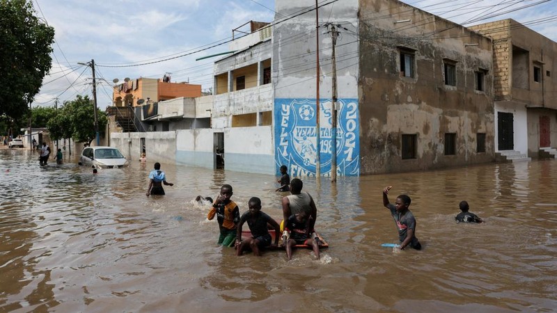 Anak-anak bermain di jalan yang tergenang air setelah hujan deras di Dakar, Senegal, pada 5 Oktober 2026.
