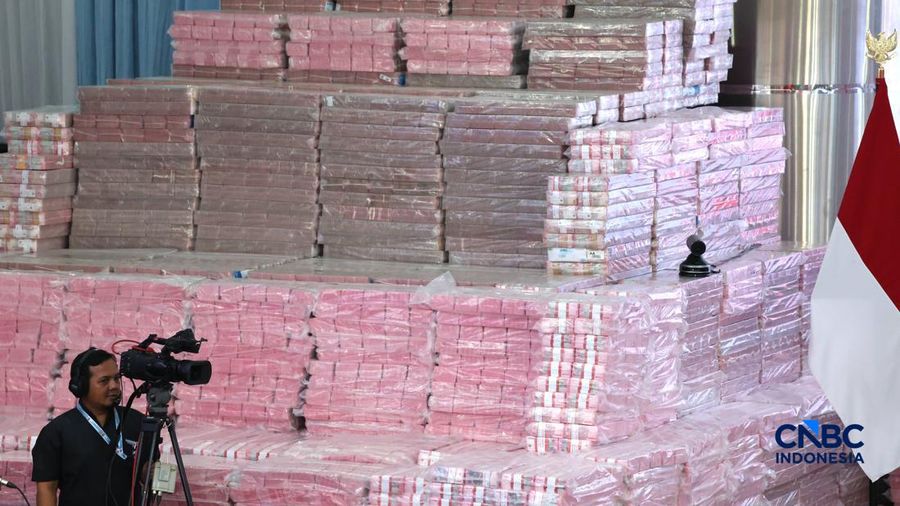 Pekerja berdiri di depan Tumpukan uang sekitar Rp132,241,335,681,910,13 dipajang dalam kegiatan penyerahan denda administratif dan penyelamatan keuangan negara serta penguasaan kembali kawasan hutan di kompleks Kejaksaan Agung, Jakarta, Selasa (06/10/2026).