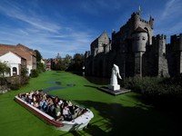 Sebuah kapal wisata melintasi bagian Sungai Lys yang tertutup tanaman air duckweed di depan Kastil Gravensteen di Ghent, Belgia, pada 5 Oktober 2026. (REUTERS/Stephanie Lecocq)