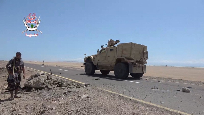 Seorang pejuang pemerintah Yaman yang didukung Arab Saudi berdiri di tepi jalan saat sebuah kendaraan militer melintas, dalam sebuah operasi yang menurut pasukan pemerintah merupakan upaya maju melawan kelompok Houthi yang didukung Iran, di dekat Dhubab, Kegubernuran Taiz, Yaman; gambar ini diambil dari video yang dirilis pada 5 Oktober 2026. (Southern Giants Brigades/Handout via REUTERS)