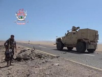 Seorang pejuang pemerintah Yaman yang didukung Arab Saudi berdiri di tepi jalan saat sebuah kendaraan militer melintas, dalam sebuah operasi yang menurut pasukan pemerintah merupakan upaya maju melawan kelompok Houthi yang didukung Iran, di dekat Dhu