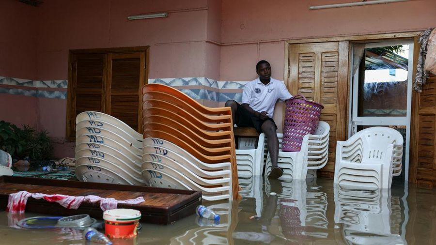 Seorang pria duduk di atas permukaan air banjir sementara perabotan dan barang-barang menumpuk di dalam rumah yang terendam air setelah hujan deras di Dakar, Senegal, pada 5 Oktober 2026.