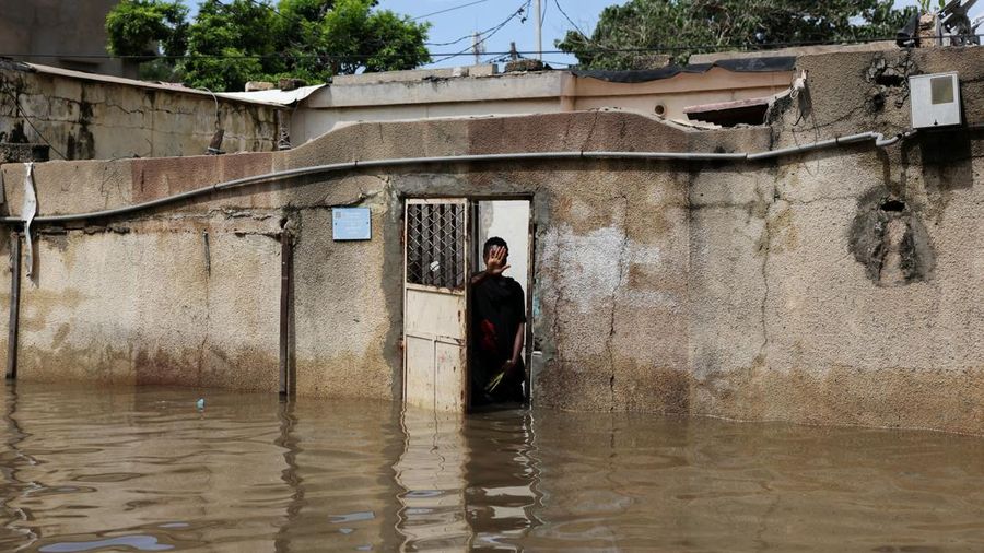 Seseorang berdiri di balik pembatas sebuah rumah yang terendam banjir setelah hujan deras di Dakar, Senegal, pada 5 Oktober 2026.