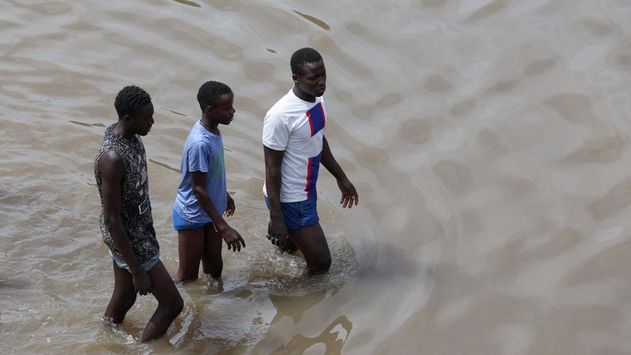 Warga berjalan menerjang jalan yang tergenang air setelah hujan deras di Dakar, Senegal, pada 5 Oktober 2026.