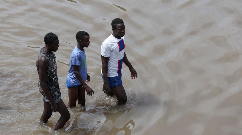 Warga berjalan menerjang jalan yang tergenang air setelah hujan deras di Dakar, Senegal, pada 5 Oktober 2026.