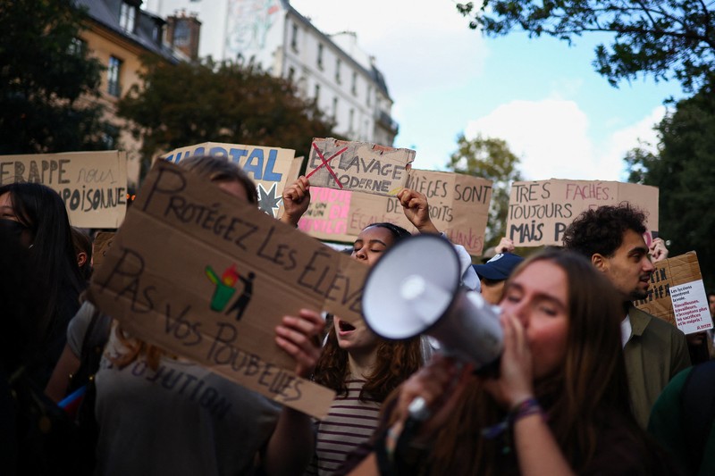 A person carries the French national flag as French high school and university students attend a demonstration in Nantes, part of a nationwide day of protests and blockades to demand better school conditions in France, October 8, 2026. REUTERS/Stephane Mahe