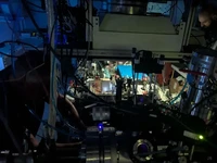 Ruang vakum yang berisi kristal torium; kanan atas: Luca Toscani de Col sedang menyetel laser. (Dok. Matthias Heisler, TU Wien)