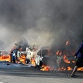 A resident walks past burning vehicles during unrest following anti-migrant protests, where residents clashed with foreign-owned shopkeepers, and vehicles were set alight after months of anti-migrant demonstrations that have drawn international criti