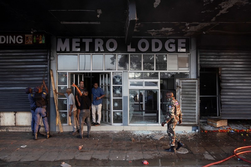 A police officer walks past burning vehicles during unrest following anti-migrant protests, where residents clashed with foreign-owned shopkeepers, and vehicles were set alight, after months of anti-migrant demonstrations that have drawn international criticism, in Soweto, South Africa, October 8, 2026. REUTERS/Stringer