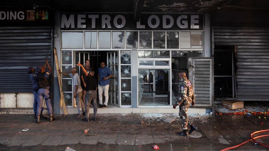 A police officer walks past burning vehicles during unrest following anti-migrant protests, where residents clashed with foreign-owned shopkeepers, and vehicles were set alight, after months of anti-migrant demonstrations that have drawn internationa