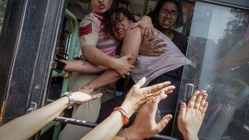 Polisi wanita berupaya mencegah seorang pengunjuk rasa yang telah diamankan melarikan diri dari bus saat aksi protes oleh Cockroach Janta Party (CJP)—yang menuntut pengunduran diri Kepala Komisioner Pemilihan Umum India, Gyanesh Kumar—di dekat lokasi unjuk rasa di New Delhi, India, pada 10 Oktober 2026.