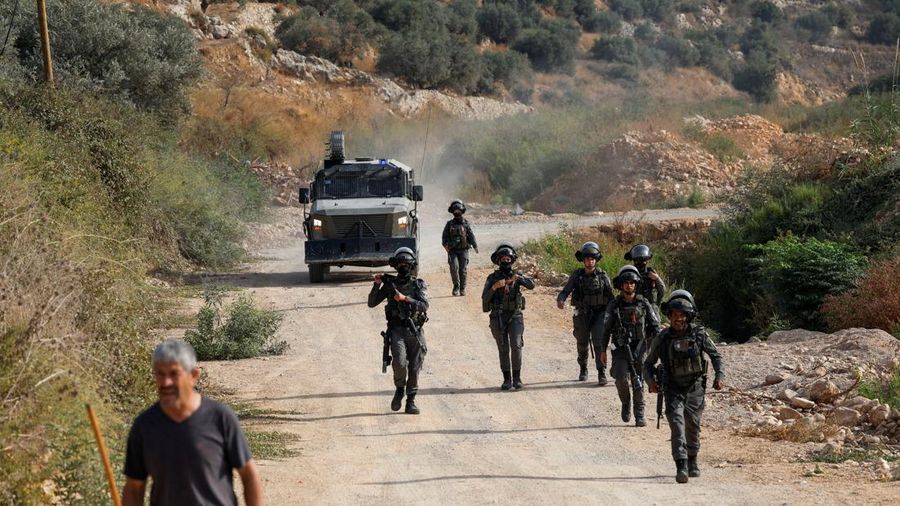 Seorang pria Palestina berjalan di dekat tentara Israel sementara para petani Palestina—yang sedang memetik zaitun pada musim panen—bereaksi saat terjadi bentrokan dengan pemukim Israel di kebun zaitun milik warga Palestina di desa Deir Abu Mishal, dekat Ramallah, di Tepi Barat yang diduduki Israel, pada 10 Oktober 2026.