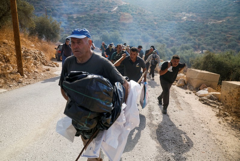 Warga Palestina yang sedang memanen zaitun dan para aktivis asing bereaksi saat terjadi bentrokan dengan pemukim Israel di kebun zaitun milik warga Palestina di desa Deir Abu Mishal&mdash;dengan kepulan asap gas air mata terlihat di latar belakang&mdash;di dekat Ramallah, Tepi Barat yang diduduki Israel, pada 10 Oktober 2026. (REUTERS/Mohamad Torokman)
