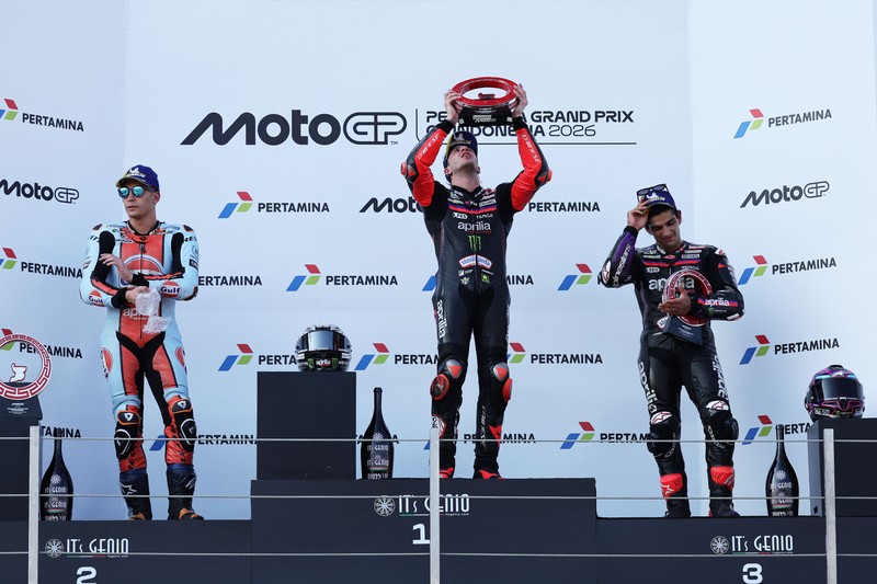 Pembalap Aprilia Racing Marco Bezzecchi merayakan kemenangan di atas podium sambil mengangkat trofi setelah memenangi balapan MotoGP Grand Prix Indonesia 2026, bersama pembalap Trackhouse MotoGP Team Raul Fernandez yang finis kedua dan pembalap Aprilia Racing Jorge Martin yang menempati posisi ketiga, di Sirkuit Internasional Mandalika, Mandalika, Indonesia, (11/10/2026). (REUTERS/Willy Kurniawan)