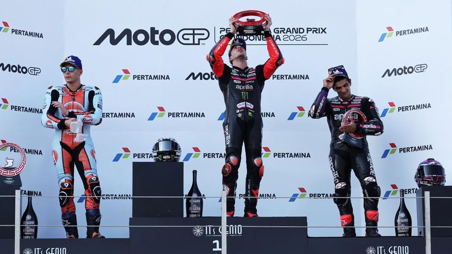 Pembalap Aprilia Racing Marco Bezzecchi merayakan kemenangan di atas podium sambil mengangkat trofi setelah memenangi balapan MotoGP Grand Prix Indonesia 2026, bersama pembalap Trackhouse MotoGP Team Raul Fernandez yang finis kedua dan pembalap April