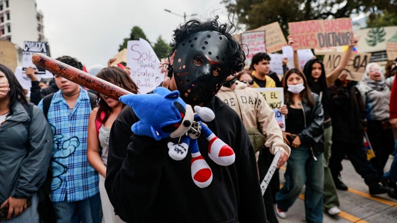 Seorang pengunjuk rasa muda yang mengenakan topeng hoki dan memegang boneka Sonic berpose untuk difoto saat demonstrasi yang dipimpin oleh kaum muda menentang pemerintahan Presiden Ekuador Daniel Noboa—yang menuntut akses lebih baik terhadap layanan kesehatan, pendidikan, dan pekerjaan yang layak—di Quito, Ekuador, pada 10 Oktober 2026.