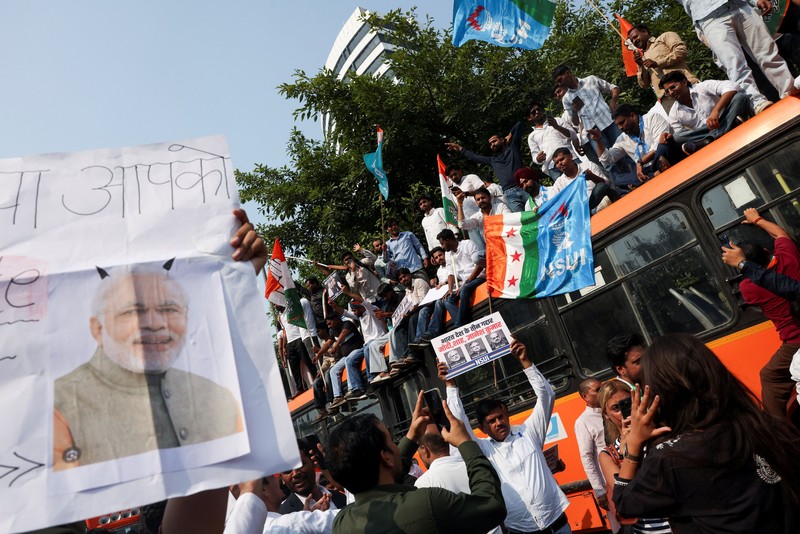 Para pendukung partai oposisi berdiri di atas bus dengan membawa plakat dan bendera sambil berbaris menuju Mahkamah Agung untuk memprotes revisi daftar pemilih yang kontroversial yang telah memicu kerusuhan selama beberapa hari, di New Delhi, India, 12 Oktober 2026. (REUTERS/Priyanshu Singh)