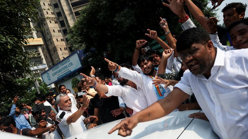 Para pendukung partai oposisi berdiri di atas bus dengan membawa plakat dan bendera sambil berbaris menuju Mahkamah Agung untuk memprotes revisi daftar pemilih yang kontroversial yang telah memicu kerusuhan selama beberapa hari, di New Delhi, India, 12 Oktober 2026. (REUTERS/Priyanshu Singh)