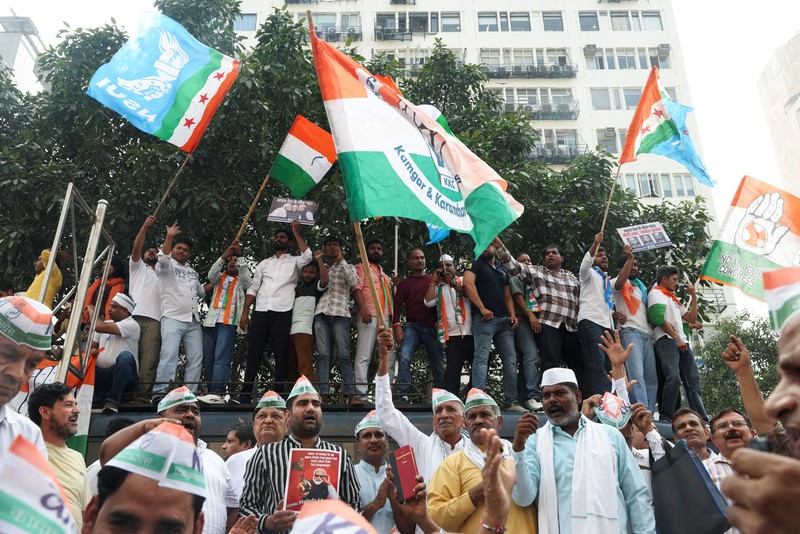 Para pendukung partai oposisi berdiri di atas bus dengan membawa plakat dan bendera sambil berbaris menuju Mahkamah Agung untuk memprotes revisi daftar pemilih yang kontroversial yang telah memicu kerusuhan selama beberapa hari, di New Delhi, India, 12 Oktober 2026. (REUTERS/Priyanshu Singh)
