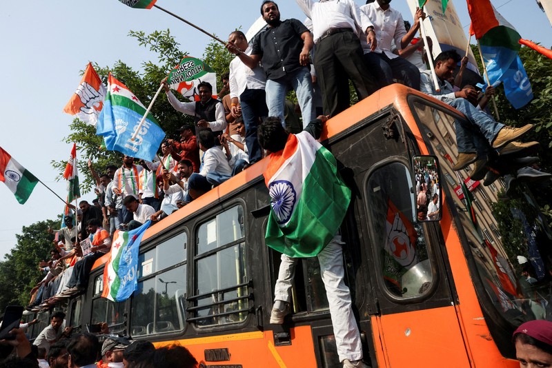 Para pendukung partai oposisi berdiri di atas bus dengan membawa plakat dan bendera sambil berbaris menuju Mahkamah Agung untuk memprotes revisi daftar pemilih yang kontroversial yang telah memicu kerusuhan selama beberapa hari, di New Delhi, India, 12 Oktober 2026. (REUTERS/Priyanshu Singh)
