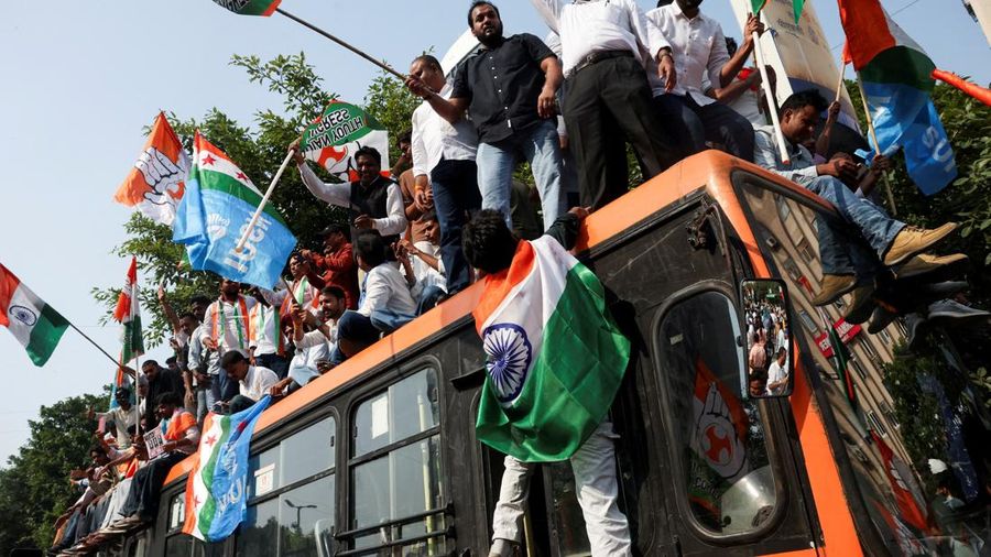 Para pendukung partai oposisi berdiri di atas bus dengan membawa plakat dan bendera sambil berbaris menuju Mahkamah Agung untuk memprotes revisi daftar pemilih yang kontroversial yang telah memicu kerusuhan selama beberapa hari, di New Delhi, India, 12 Oktober 2026. (REUTERS/Priyanshu Singh)