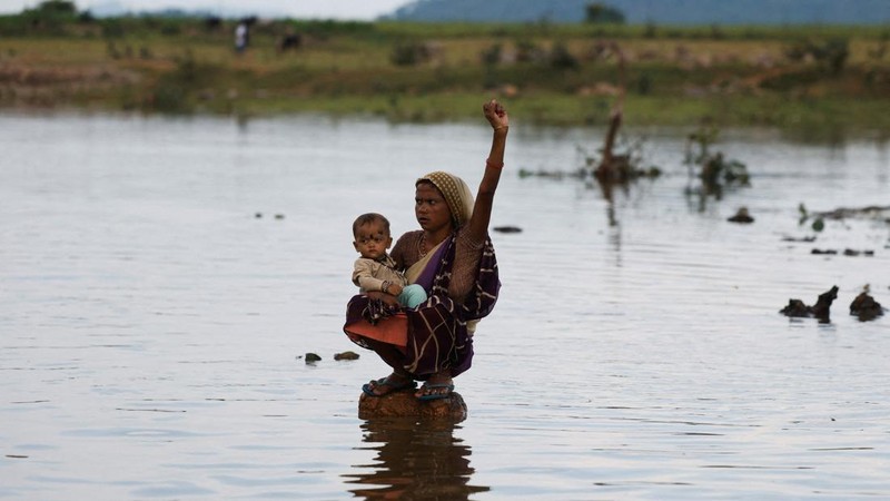 Savita Devi, anggota keluarga yang terdampak oleh Proyek Penghubung Sungai Ken-Betwa, menggendong anaknya sambil duduk di atas batu dan mengangkat kepalan tangannya sembari meneriakkan slogan-slogan yang menuntut kompensasi serta rehabilitasi yang layak dalam sebuah aksi protes di dekat Bendungan Majhgawan di Sungai Ken, Ajaygarh, Madhya Pradesh, India, pada 19 September 2026.